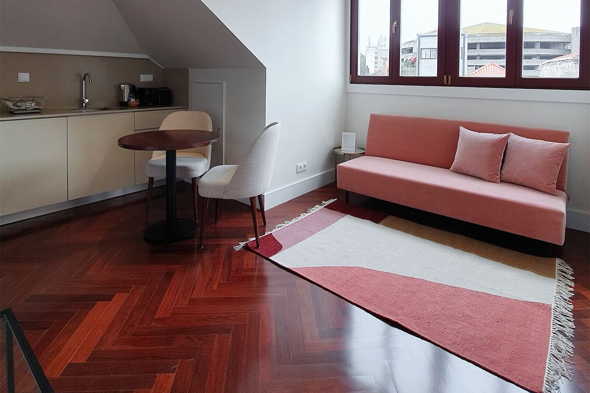 A modern living space with a herringbone wood floor, a herringbone ceiling, a herringbone staircase, a herringbone dining table, a herringbone sofa, and a herringbone window.