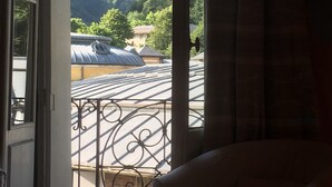 Quarto com vista para montanhas e varanda com grades de metal.