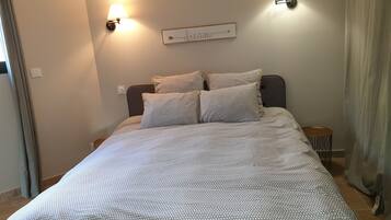 A neatly made bed with a patterned bedspread, two wall-mounted lamps, and a directional sign on the wall.
