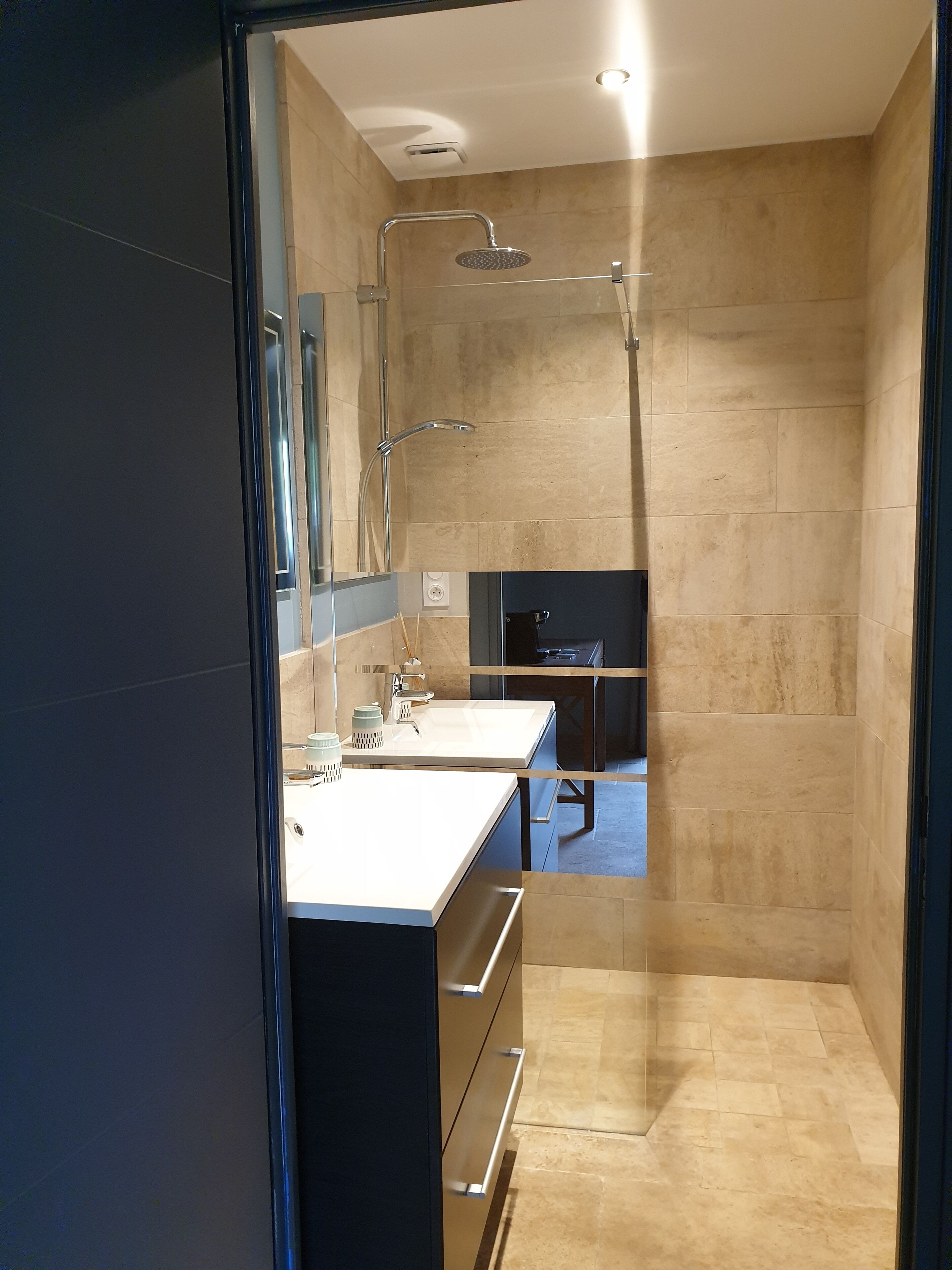 A modern bathroom with a glass shower enclosure, a vanity with a mirror, and a sink.