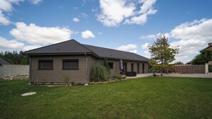 A single-story house with a sloped roof, a front porch, and a well-maintained lawn. - Cosy Wood House (Laubressel)