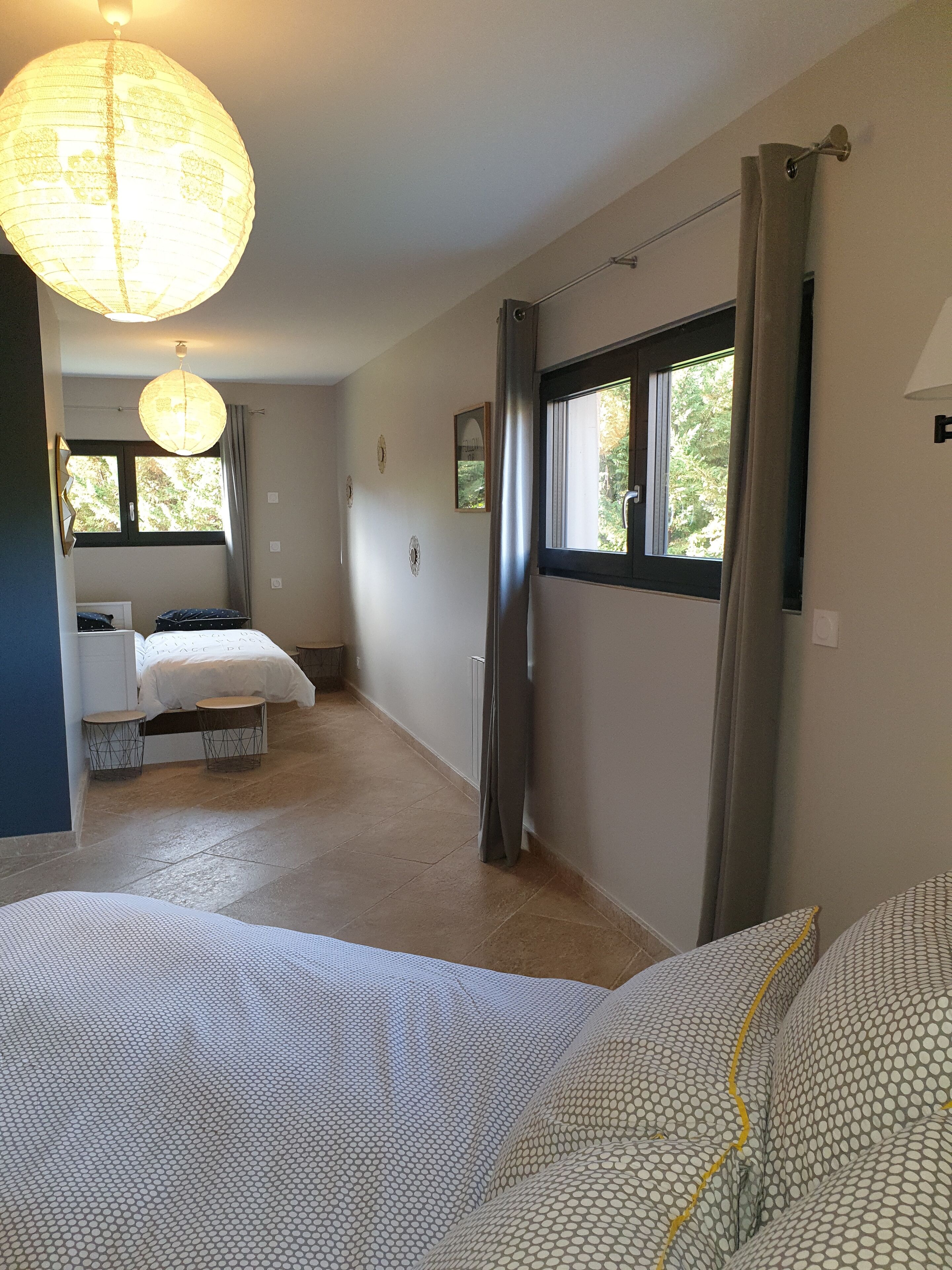 Habitació d'hotel amb un llit gran, un altre més petit, zona de seients amb una taula i una finestra amb cortines.