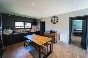 Una cocina moderna con armarios oscuros, una mesa de madera y un reloj de pared grande.