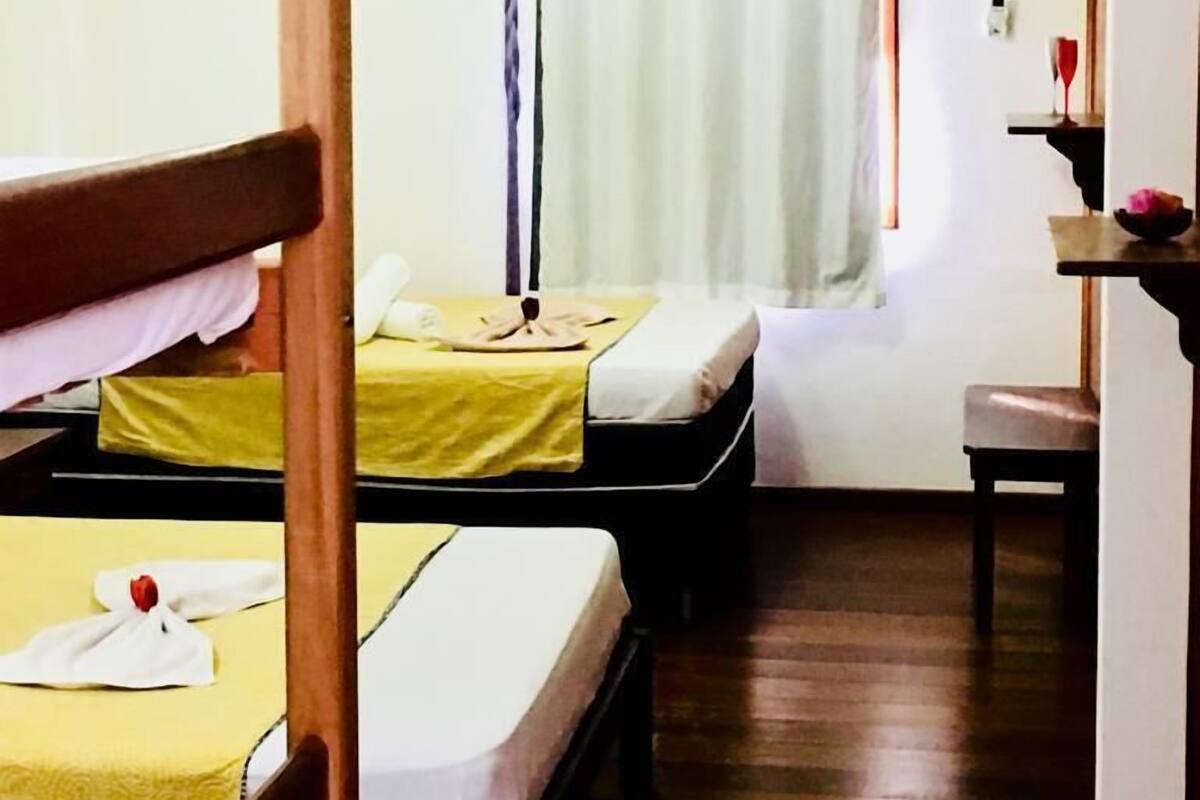 Una habitación con dos camas, un escritorio y una lámpara de pie.