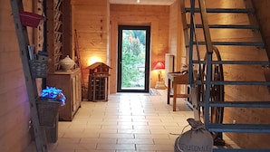 Un interior de madera con una escalera, un reloj y una puerta que da al exterior.