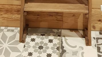 Una estantería de madera contra una pared de madera con suelo de baldosas.