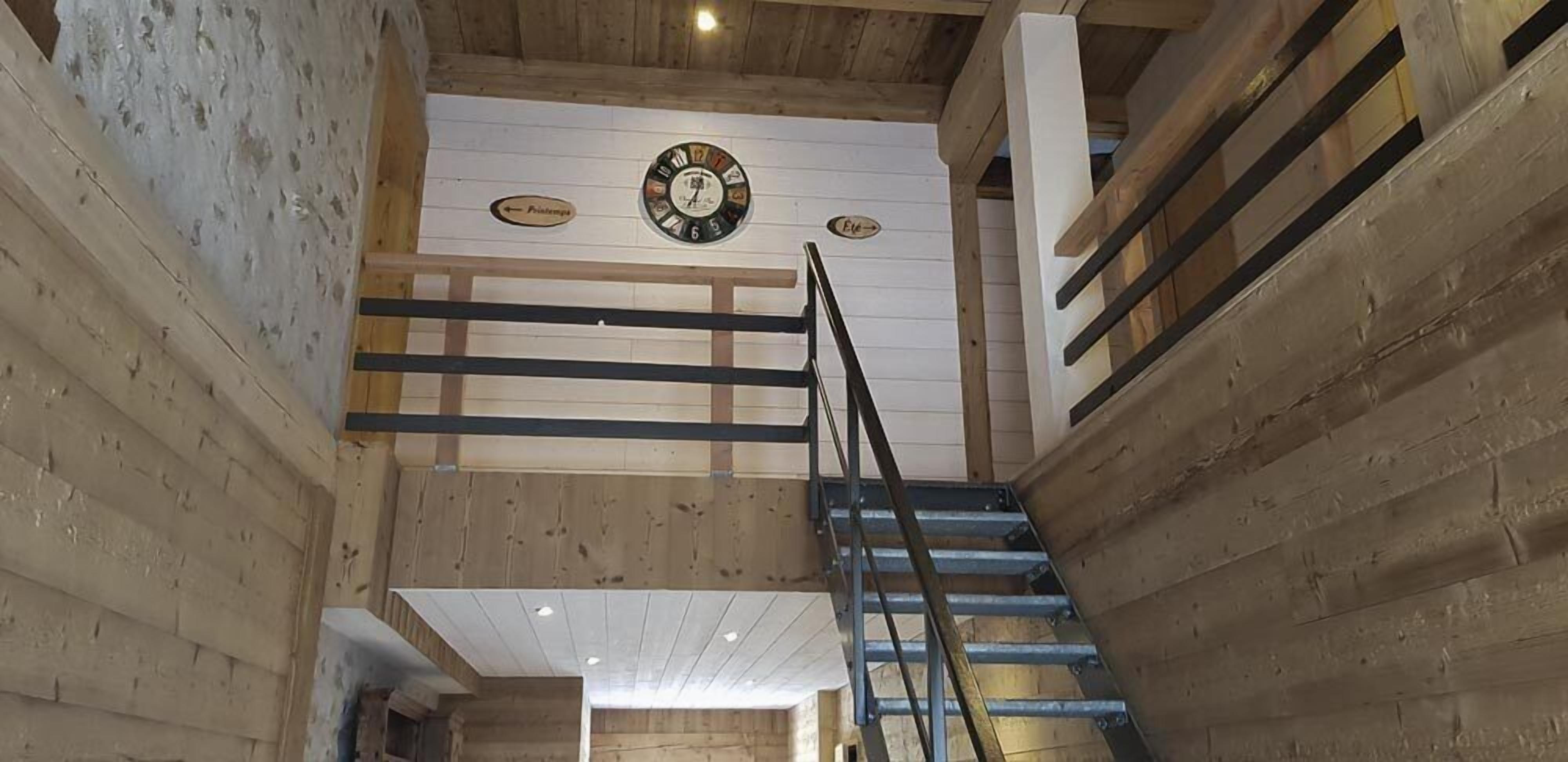 Een houten interieur met een trap, een klok en bewegwijzering.