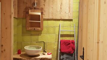 A bathroom with a wooden vanity, a sink, a mirror, and a towel rack.