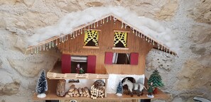 Una maqueta de casa de madera con techo nevado, una ventana pequeña y una chimenea.