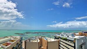 A coastal cityscape with buildings overlooking turquoise waters and a clear sky.