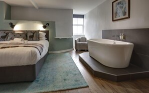 Un dormitorio moderno con una cama grande, una zona de estar y una bañera independiente.