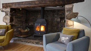 A cozy room with a stone fireplace, two armchairs, and a floor lamp.