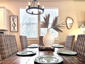 Enjoy meals in this dining area with a rustic table, wicker chairs, and a chandelier.