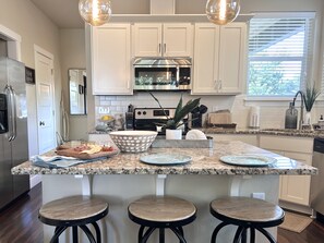Enjoy cooking in this well-equipped kitchen with a central island, stainless steel appliances, and ample lighting.