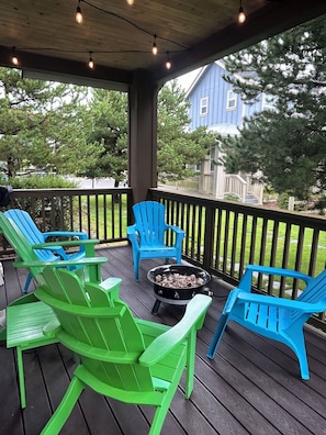 Relax on the covered deck with Adirondack chairs and a grill, surrounded by lush greenery.