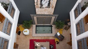 A rooftop terrace with a seating area, a small table with a red rug, and decorative items. - Riad Lamzia (Marrakech)
