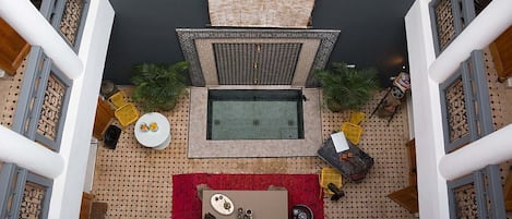 A rooftop terrace with a seating area, a small table with a red rug, and decorative items.
