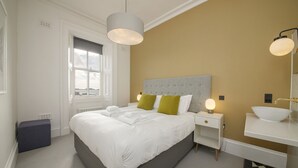 Un dormitorio moderno con una cama grande, lámparas de noche, una mesita de noche y vistas al exterior a través de una ventana.