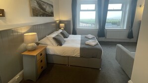 A hotel room with a bed, bedside table, lamp, and a painting on the wall. - The Wight Mouse Inn (Ventnor)