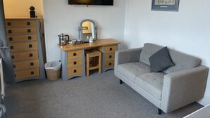 A room with a grey sofa, a wooden desk with drawers, a flat-screen TV, and a framed picture on the wall. - The Wight Mouse Inn (Ventnor)