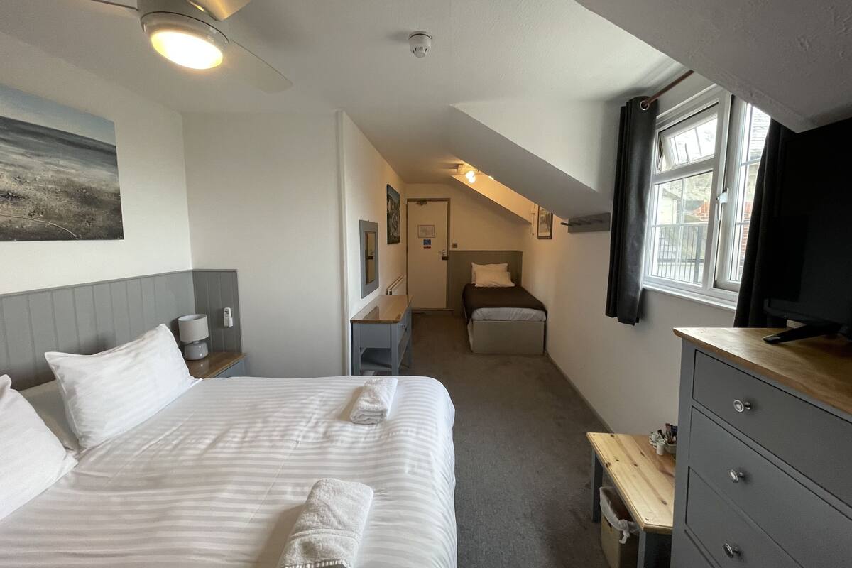 A hotel room with a bed, a desk, a chair, a TV, and a window.
