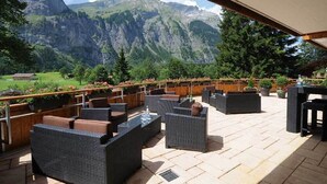 An outdoor seating area with wicker furniture and a view of mountains. - Landgasthof Ruedihus (Kandersteg)