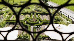 A garden with a circular hedge maze, a paved walkway, and a fence. - Landgasthof Ruedihus (Kandersteg)