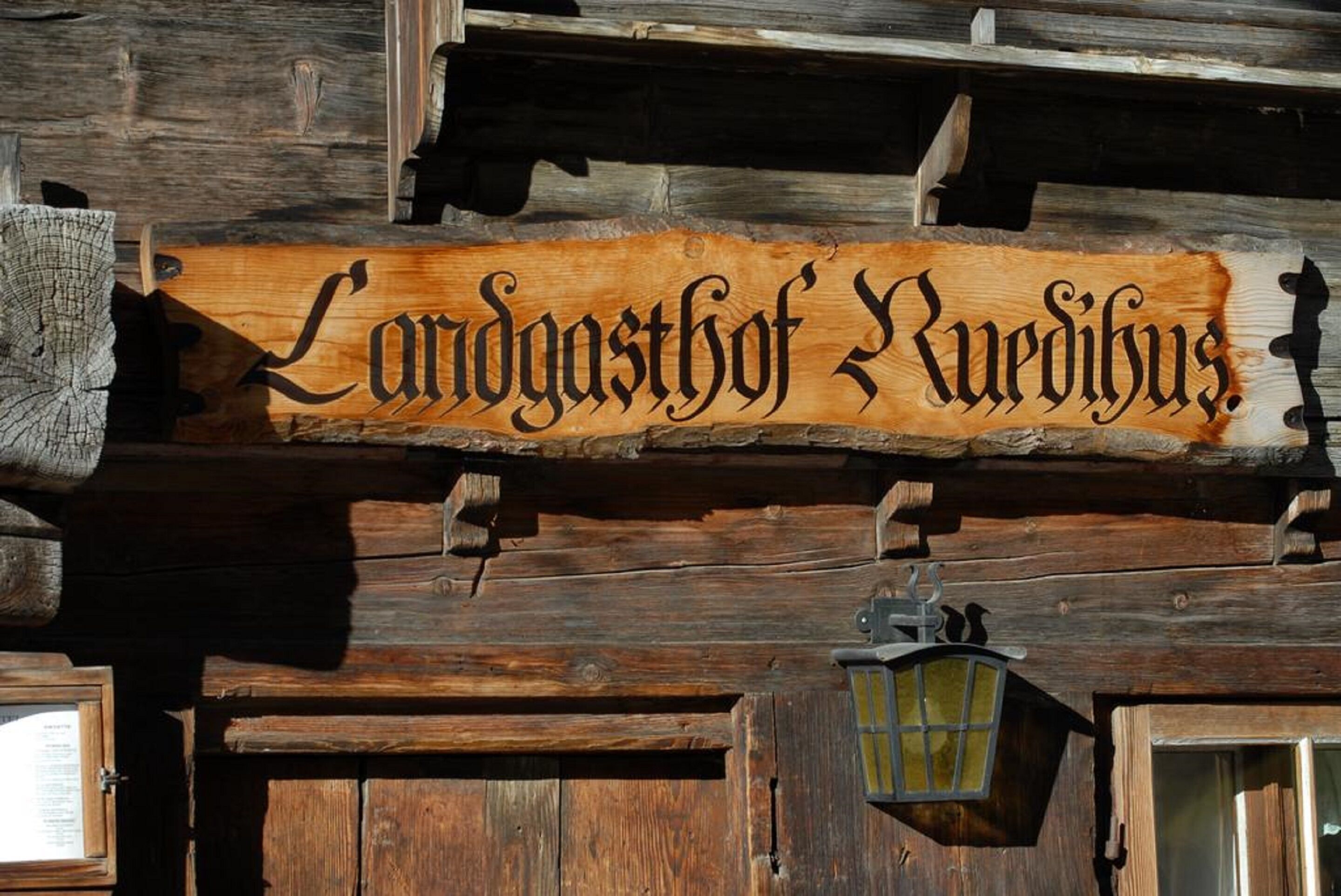 En träskylt med inristad text, monterad på en rustik trävägg.