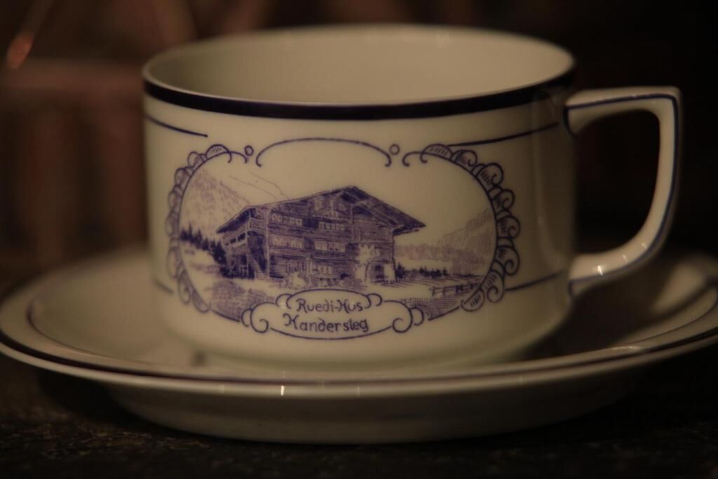 A ceramic cup with a drawing of a house and the text "Ruedi-Hus Kandersteg".
