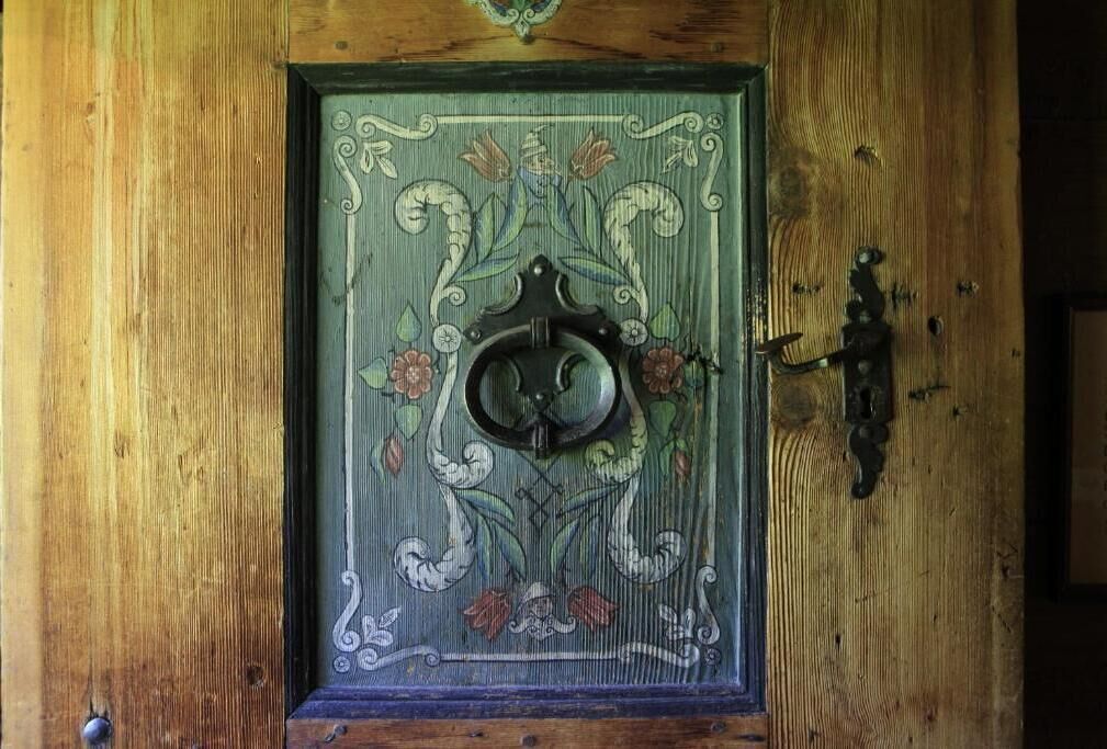 A wooden door with an ornate metal knocker and a decorative glass panel.