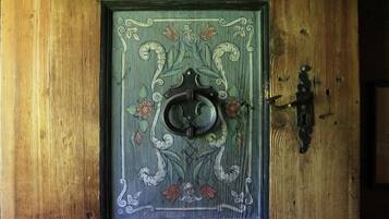 A wooden door with an ornate metal knocker and a decorative glass panel.