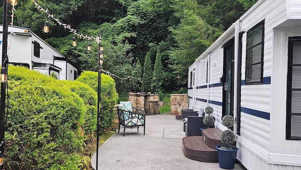 A mobile home with a patio area, outdoor seating, and potted plants. - Serene Mountain Resort For 2 (Gatlinburg)
