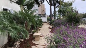 Un sendero de jardín que lleva a una casa de fachada blanca y un camino de piedra.