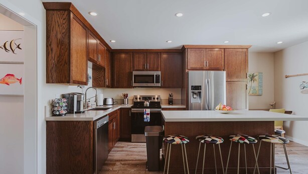 Una cocina moderna con armarios de madera, electrodomésticos de acero inoxidable y una isla central con taburetes.