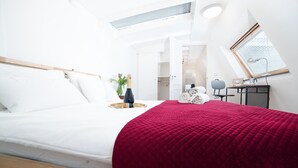 A modern bedroom with a bed, a red blanket, a bottle of champagne, and a small table with towels. - Dase Bed & Breakfast (Amsterdam)