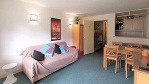 A compact living space with a sofa, a dining table, and a kitchenette. - South-Facing Studio for 4 with Balcony, Ski-In/Ski-Out Access (La Mongie)