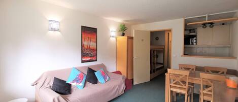 A compact living space with a sofa, a dining table, and a kitchenette.