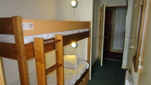 A bunk bed room with a night light, a door leading to another room, and a sign on the wall. - South-Facing Studio for 4 with Balcony, Ski-In/Ski-Out Access (La Mongie)