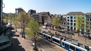 A tram in an urban setting with historic buildings and a clear sky.