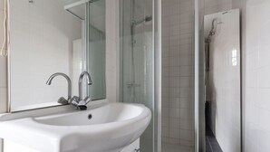 A bathroom with a white sink, a mirror, and a shower area.