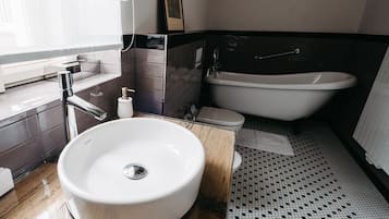 Ett modernt badrum med ett stort handfat, ett badkar och en toalett.