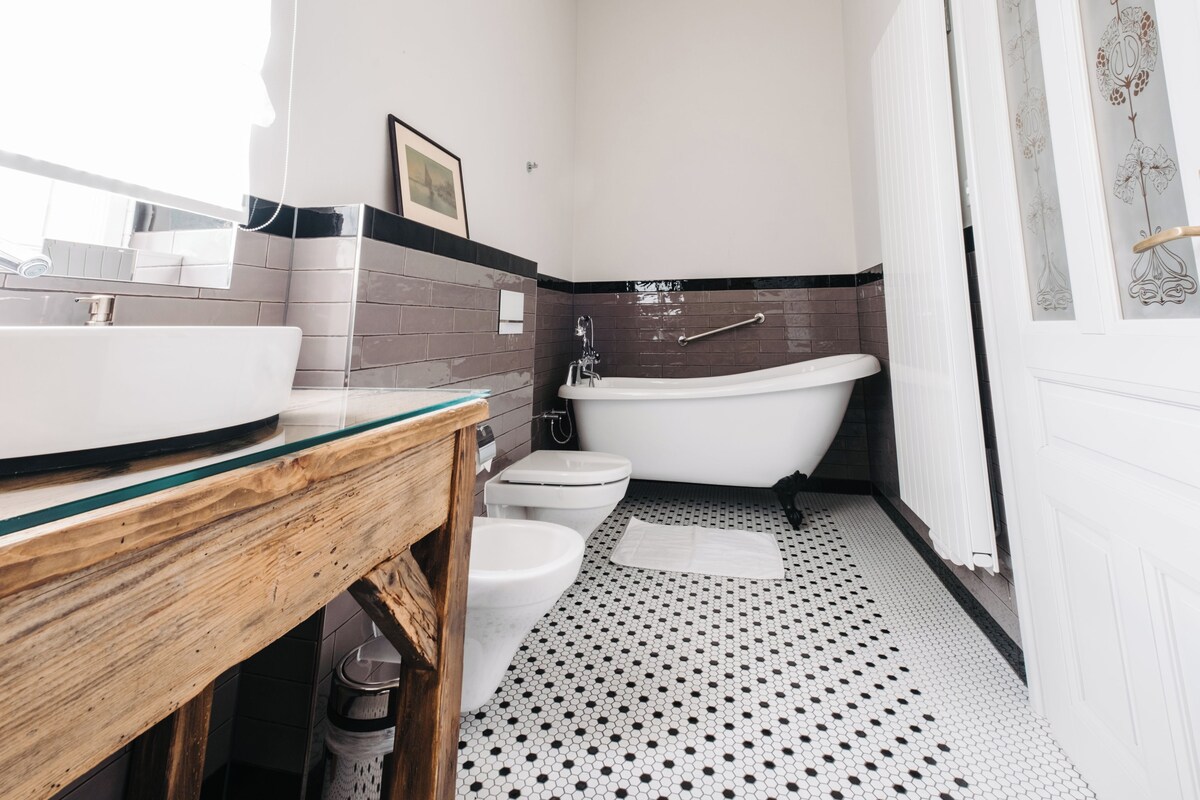 Un baño con bañera independiente, lavamanos y dos inodoros.