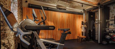 Un gimnasio con equipo de ejercicio, una pared de madera y una pared de piedra.