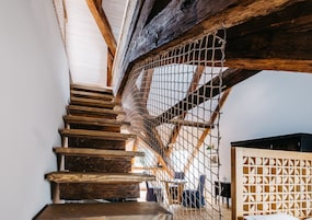 Una escalera de madera con una barandilla de malla metálica, un cabecero de madera y vistas al espacio interior.
