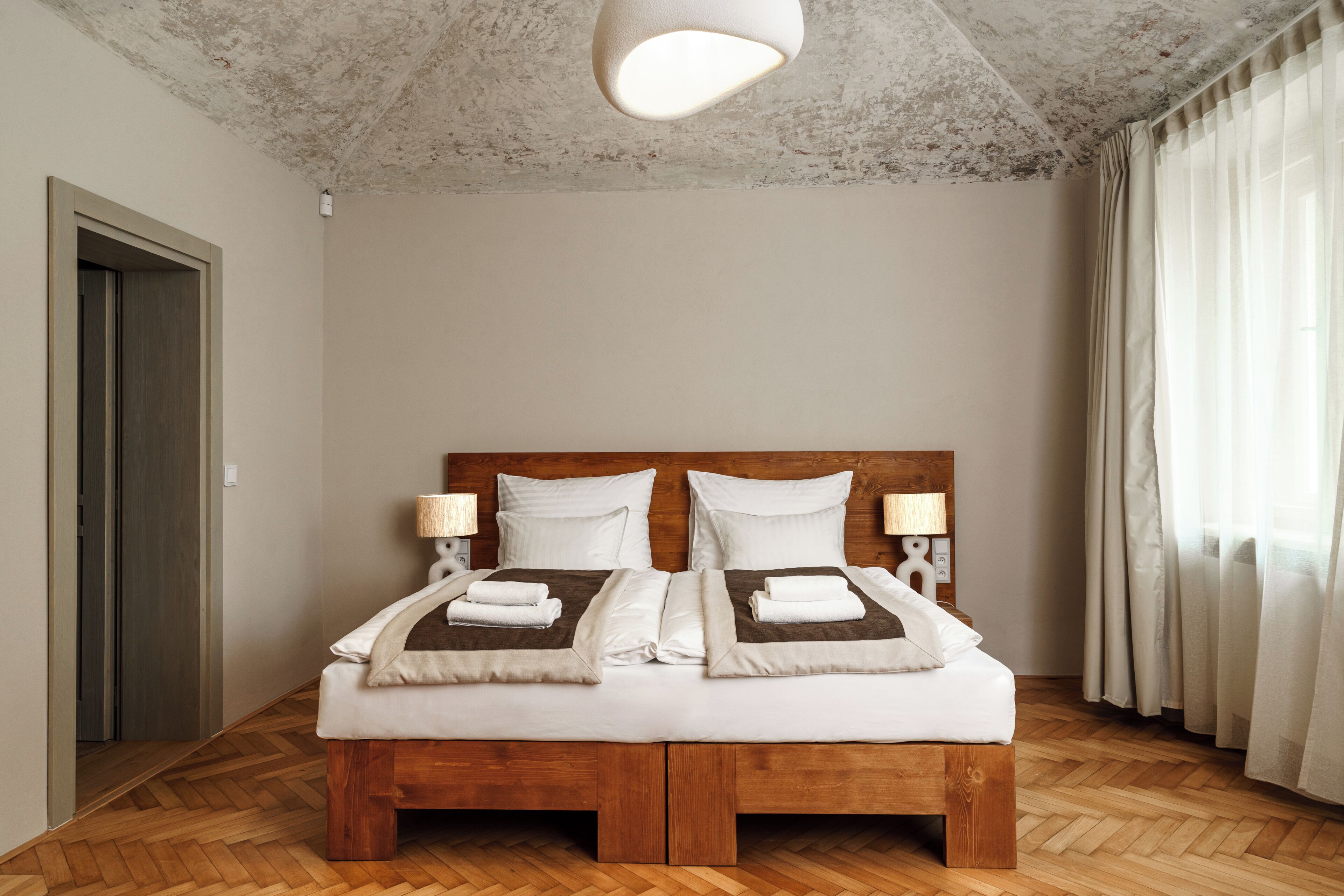 A double bed with a wooden frame, two bedside tables with lamps, and a ceiling light fixture.