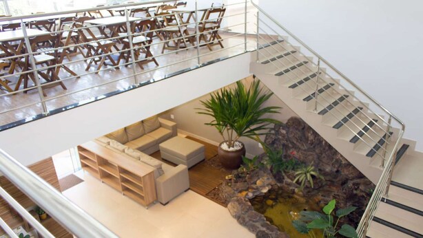 A spacious indoor area with a seating area, a staircase, and a small indoor garden. - Hotel Oliveiras (Trindade)