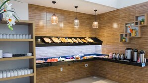 A buffet area with various food items, a coffee station, and a shelf with condiments. - Hotel Oliveiras (Trindade)