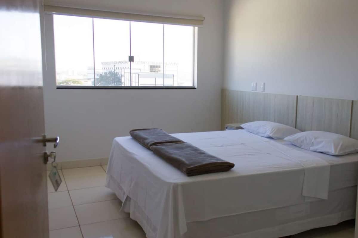 A bedroom with a bed, a window, and a door.