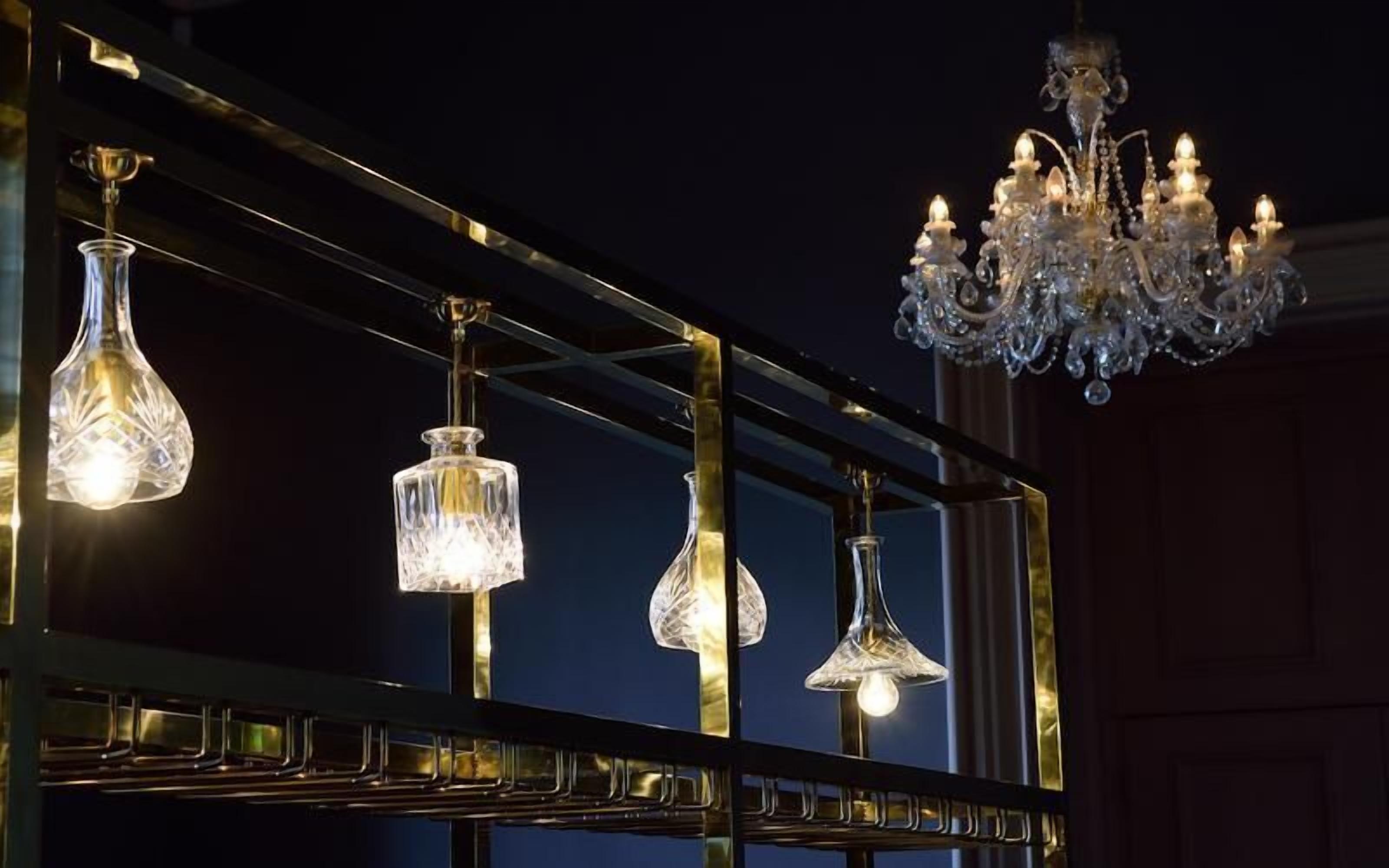 A chandelier and three hanging light fixtures with a reflective surface.