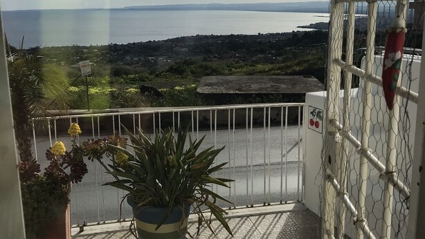 Ein Balkon mit Blick auf ein Gewässer und eine entfernte Landschaft.
